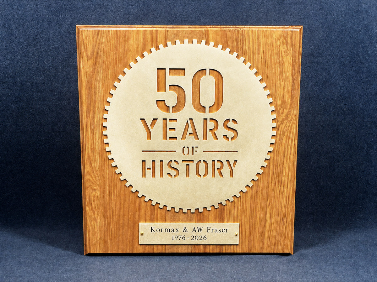 Photo of brass plaque on rimu board for 50 Years of History with AW Fraser and Kormax